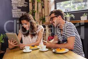 Young couple using digital tablet in cafeteria