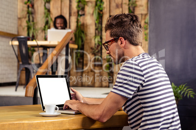 Portrait of young man sitting at table using laptop