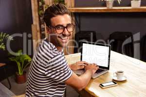 Young man using laptop in cafeteria