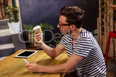 Young man looking at disposable cup in cafeteria