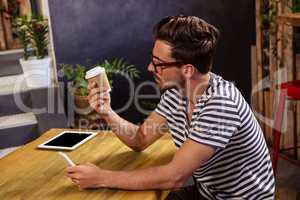 Young man looking at disposable cup in cafeteria