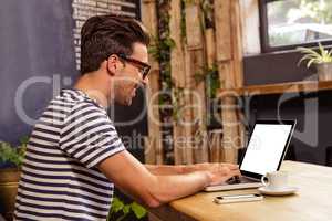 Young man using laptop in cafeteria