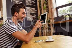 Young man using digital tablet in cafeteria