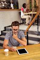 Young man sitting at table using a smartphone