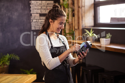Smiling waitress using a bank card reader