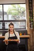 Portrait of waitress holding a tray with tartlets