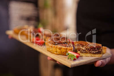 Close up of hands holding a tray with slices of pie