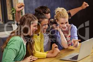 Smiling friends using laptop together