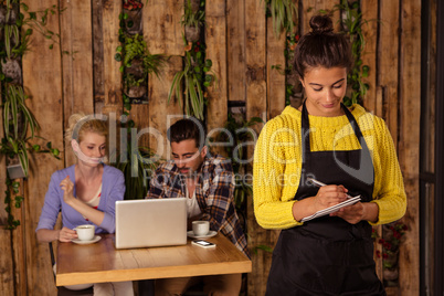 A waitress is taking the order in front of the two friends