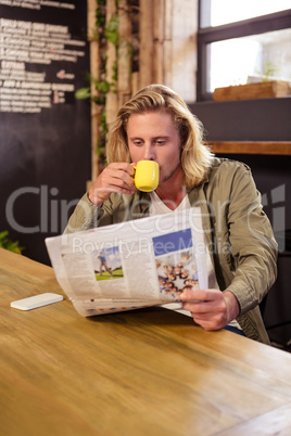 Man drinking a coffee while is reading a newspaper