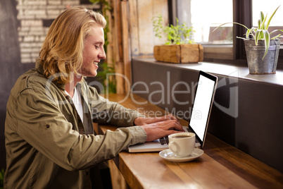 Young man using laptop in cafeteria