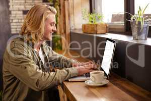 Young man using laptop in cafeteria