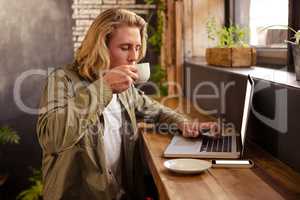 Man drinking coffee and using laptop