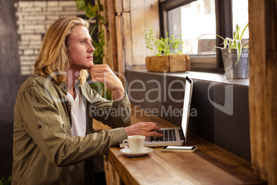 Young man using laptop in cafeteria