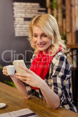 Woman drinking coffee and using smartphone