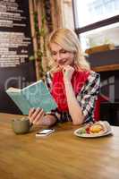 Young woman reading novel in cafeteria