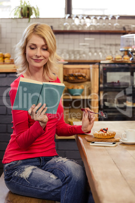 Woman reading a book and eating a cake