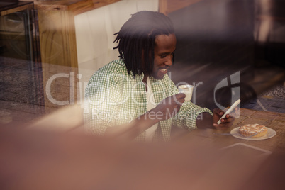 Man drinking coffee and using smartphone