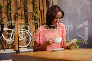 Woman drinking coffee and using smartphone