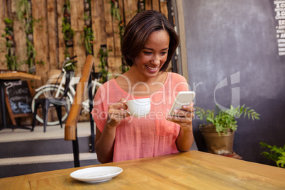 Woman drinking coffee and using smartphone