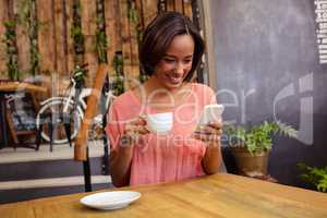 Woman drinking coffee and using smartphone