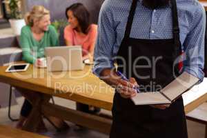 Waiter taking order in his book
