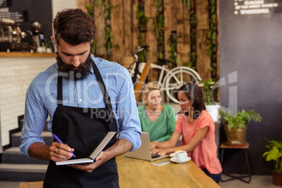 Waiter taking order in his book