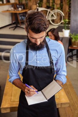 Waiter taking order in his book