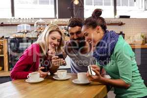 Friends using smartphones sitting