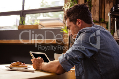 Man drinking coffee and using tablet