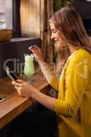 Woman using tablet and drinking milkshake