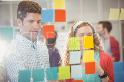 Business people looking at post it on the wall