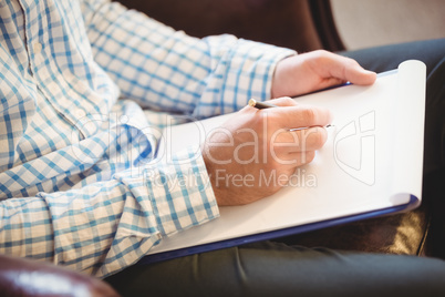 Business man writing on his clipboard