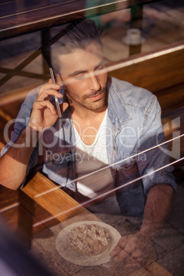 Hipster man calling with someone while eating pastries