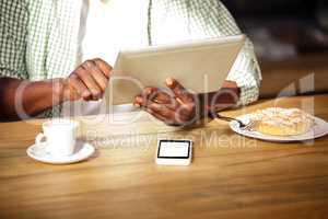 Cropped image of hipster man using tablet while eating and drinking