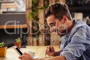 Profile view of hipster man using tablet at cafe