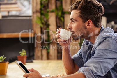 Profile view of hipster man using tablet at cafe