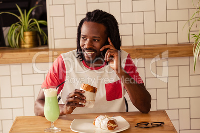 Portrait of hipster man on the phone while eating