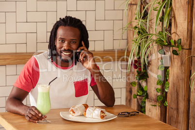 Hipster man smiling at camera while calling with smartphone