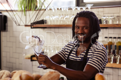 Smiling hipster worker wiping glasses