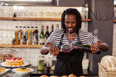 Smiling hipster employee filling glass of wine