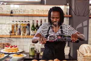 Smiling hipster employee filling glass of wine