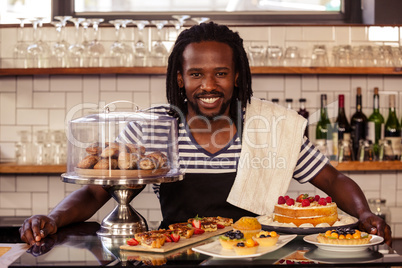 Portrait of hipster employee posing with pastries