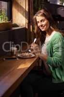 Portrait of smiling casual woman eating pastry