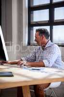 Portrait of businessman smiling and working on his computer