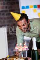 Portrait of businessman blowing out the candles for his birthday