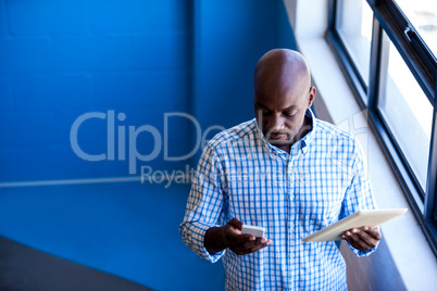 Casual businessman holding a mobile phone and tablet computer