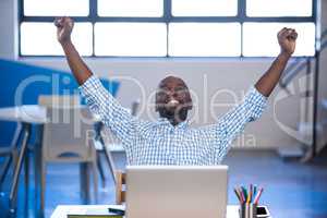 Businessman raising his arms front of laptop