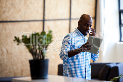 Casual businessman calling and looking his tablet computer