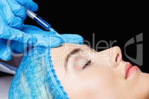 Woman receiving botox injection on her forehead